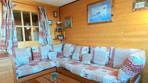Une pièce chaleureuse avec un canapé en bois, une table basse en bois et une fenêtre avec des rideaux.
