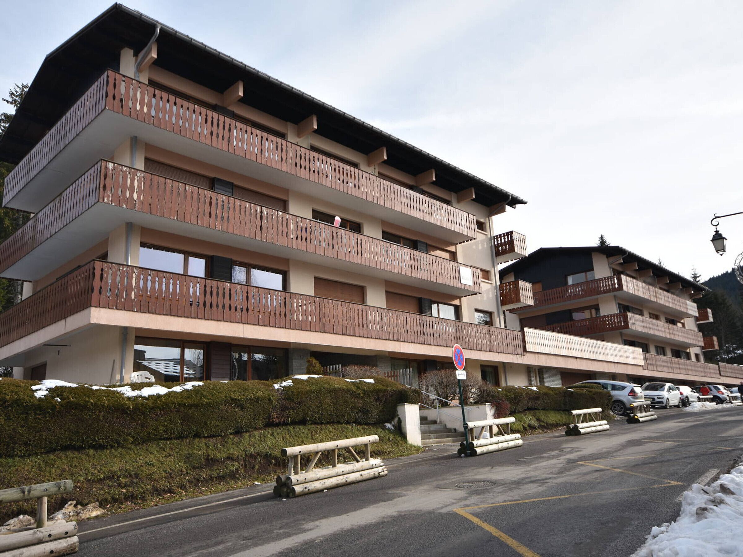 Un hotel a più piani con balconi, un'area di parcheggio e un paesaggio innevato.