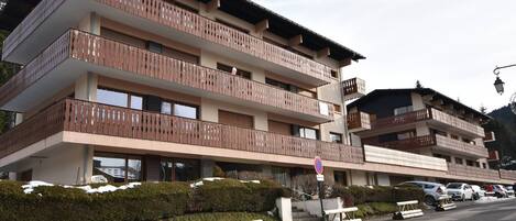 A multi-story hotel with balconies, a parking area, and a snowy landscape.