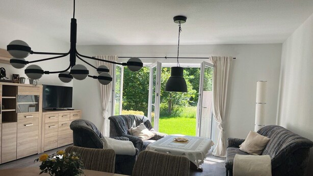 Een moderne woonkamer met een eethoek, een bank, een salontafel en een televisie.