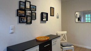Een kamer met een zwart bureau, een witte stoel en een muur versierd met ingelijste foto's.