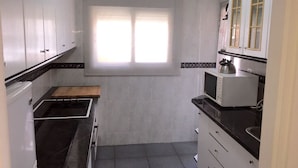 A compact kitchen with white cabinets, a black countertop, and a window providing natural light.