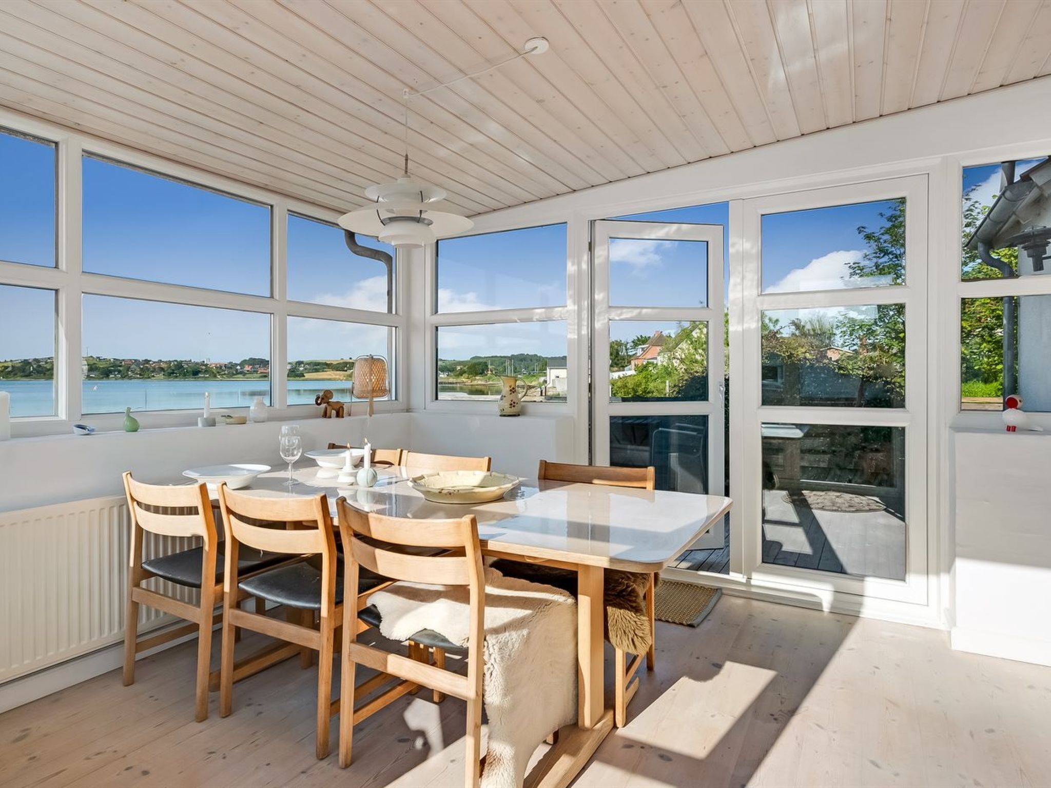 A dining area with a table and chairs, large windows, and a view of a body of water.