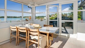 A dining area with a table and chairs, large windows, and a view of a body of water.