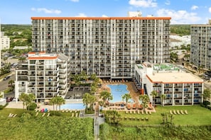 Um hotel moderno com vários sacadões, piscina e jardim ajardinado.