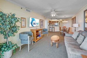 A living room with a sofa, chairs, a coffee table, a bookshelf, and a dining area with a table and chairs. - New 2BR at Horizon at 77th - Pools, Amazing Views! (Myrtle Beach)