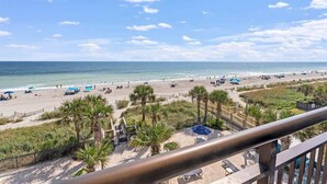 A beach with palm trees, umbrellas, and a clear sky. - NEW, Landmark Direct Oceanfront View - Pools 1BR! (Myrtle Beach)