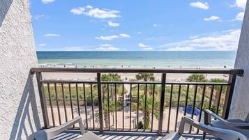 A balcony with a view of the beach and ocean.