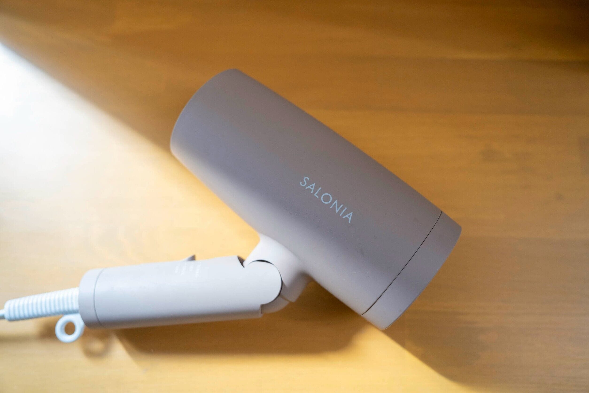 A gray electronic device with a cord and a white attachment on a wooden surface.
