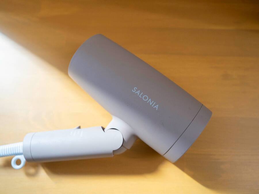 A gray electronic device with a cord and a white attachment on a wooden surface.