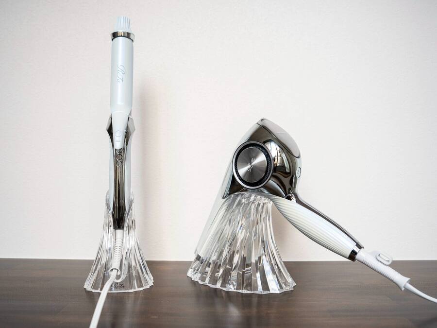 Two hair styling tools on a wooden surface against a plain wall.