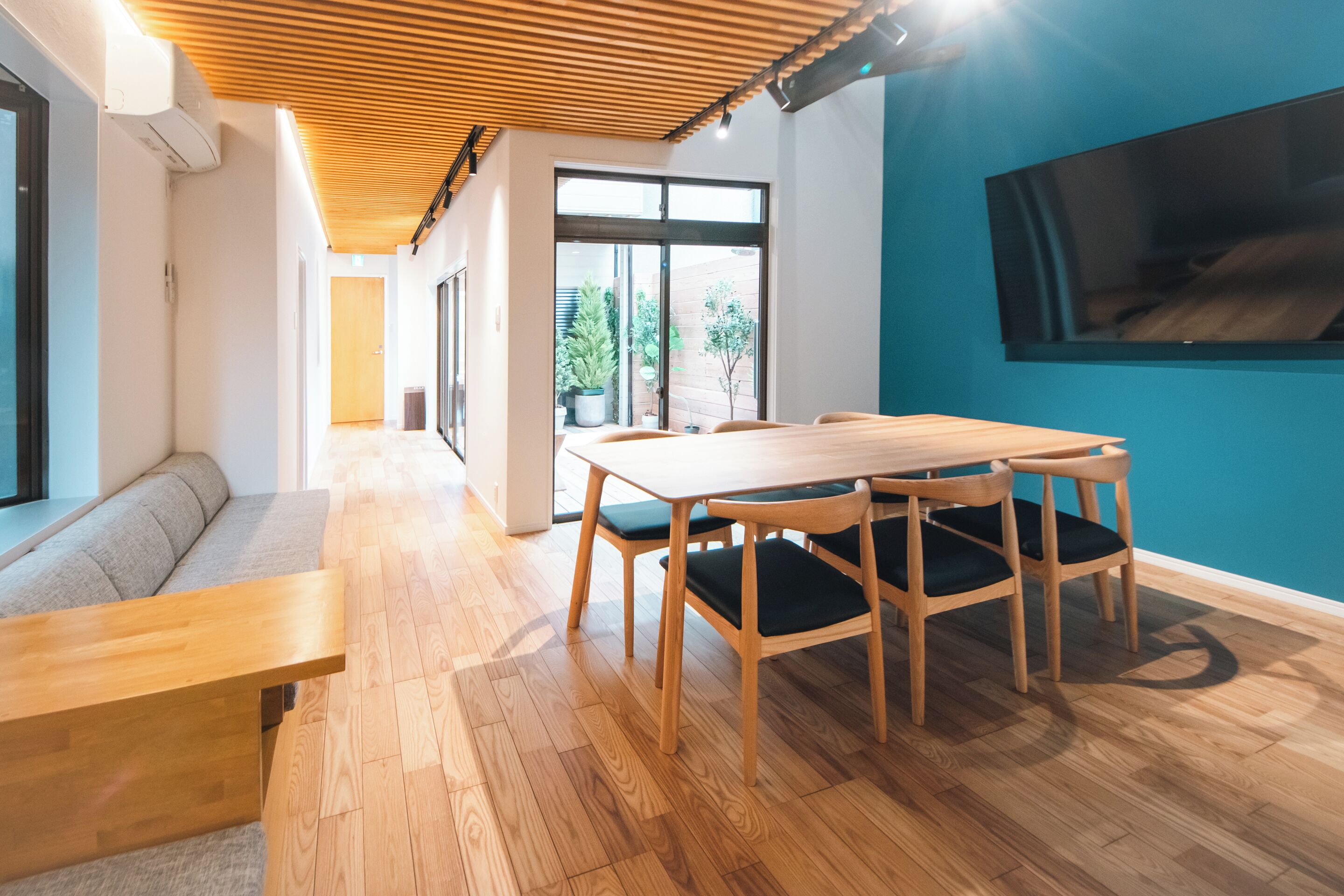 A modern interior with a wooden dining table, chairs, a bench, and a TV mounted on the wall.