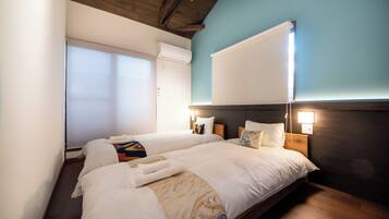 A hotel room with two beds, a large window, and a wall-mounted air conditioner.