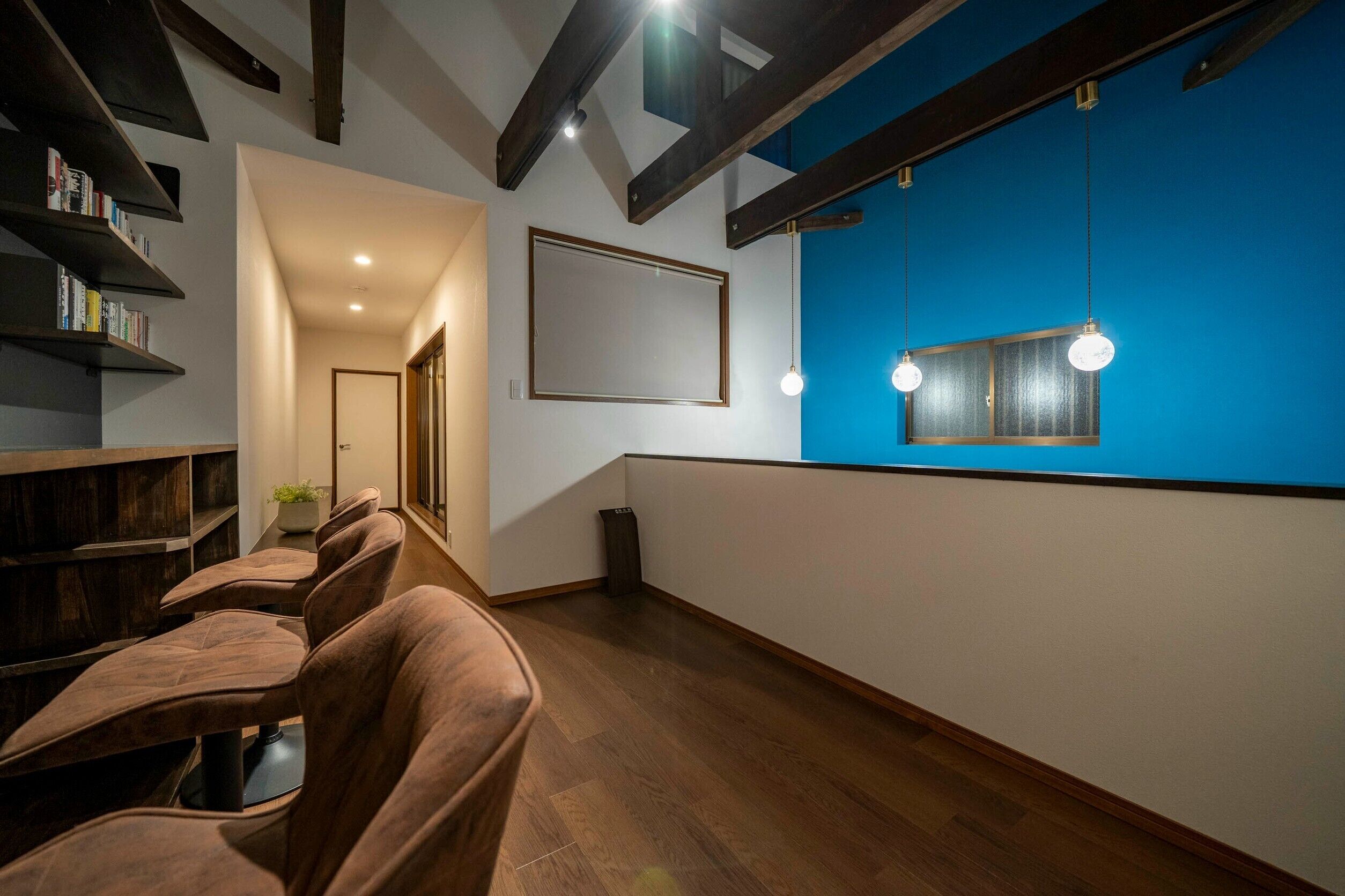 A modern interior with wooden flooring, a blue accent wall, and a seating area with brown chairs.
