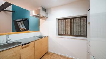 A modern kitchen with a stainless steel sink, wooden cabinets, a window with bars, and a built-in oven.