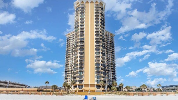 Un grand hôtel de forme cylindrique, doté de nombreux balcons et situé près d’une plage.