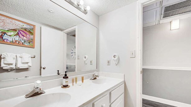 Une salle de bain avec deux lavabos, un grand miroir et un espace douche.