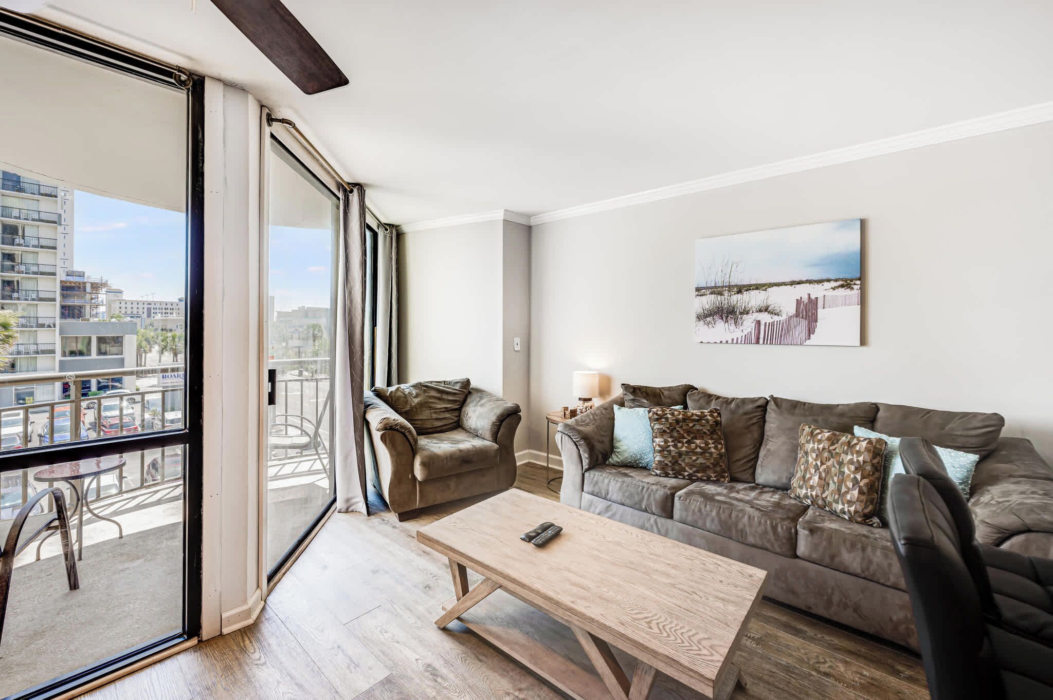 Ein modernes Wohnzimmer mit einer Couch, Sesseln, einem Couchtisch und einem großen Fenster mit Blick auf Gebäude.
