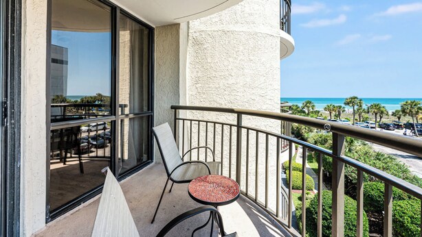 A balcony with a table and chairs, a view of the ocean, and a parking area. - Meridian Plaza 308 - 1 Bedroom (Myrtle Beach)