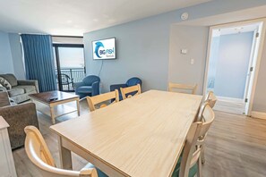 A furnished living room with a sofa, chairs, a table, and a TV displaying 'Big Fish Rentals' logo. - 3BR in Sand Dunes Resort, Oceanview, King Suite! (Myrtle Beach)