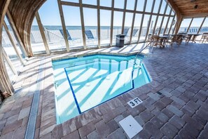 Ein Innenpool mit klarem, blauem Wasser, umgeben von Liegestühlen und einer Holzterrasse.