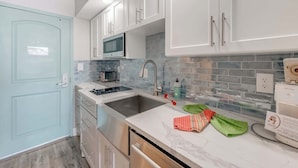 A modern kitchen with white cabinets, a stainless steel sink, a microwave, and a built-in oven.