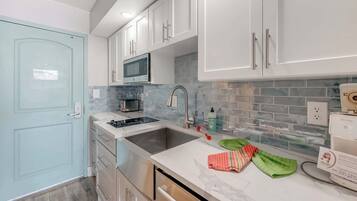 A modern kitchen with white cabinets, a stainless steel sink, a microwave, and a built-in oven.