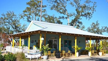 A building with a covered porch, yellow pillars, and outdoor seating.