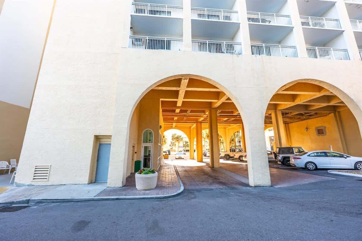A multi-story building with a covered parking area and a central archway.