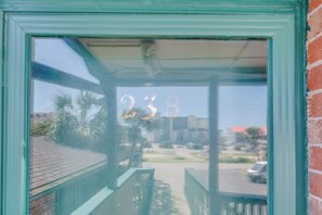 A view through a window with the number 238 visible, a street with cars, and buildings in the background. - 1BR Sea Villas in Windy Hill - Steps to the Beach! (North Myrtle Beach)
