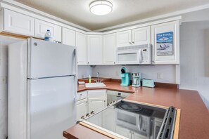 A compact kitchen with white cabinets, a refrigerator, a microwave, a sink, and a coffee maker. - 1BR Sea Villas in Windy Hill - Steps to the Beach! (North Myrtle Beach)
