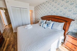 Una cama bien hecha con edredón blanco acolchado, un cabecero de madera y almohadas a juego.