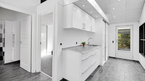 A modern kitchen with white cabinetry, a stainless steel sink, and a window with a view of greenery. - "Billa" - 450m from the sea by Interhome (Blåvand)