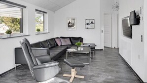 A modern living room with a sectional sofa, a coffee table, and a TV mounted on the wall. - "Billa" - 450m from the sea by Interhome (Blåvand)