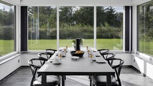 A modern dining room with a large table set for six, large windows offering a view of a grassy garden, and a high ceiling with recessed lighting. - "Billa" - 450m from the sea by Interhome (Blåvand)