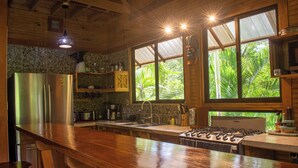 A kitchen with a wooden countertop, stainless steel appliances, and large windows overlooking greenery. - Treehouse in the Canopy close to beach - large garden with trails - Pavones wave (Pavones)