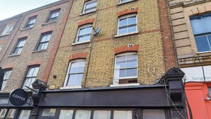 Un edificio de varios pisos con una cafetería en la planta baja, ventanas grandes y una puerta negra.