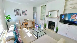Una sala de estar con sofá, mesa de centro, televisor, chimenea y comedor.