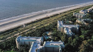 An aerial view of a coastal hotel with multiple buildings, a beach, and a swimming pool. - 2114 Windsor- Oceanfront-Just Steps from the Beach! Seasonally Heated Pool! (Hilton Head Island)