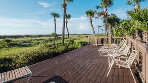 A wooden deck with white lounge chairs and a view of a grassy landscape with palm trees. - 2114 Windsor- Oceanfront-Just Steps from the Beach! Seasonally Heated Pool! (Hilton Head Island)
