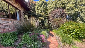 A brick building with large windows and a garden with various plants and a brick pathway. - The Tolpuddle Cottage (Warburton)
