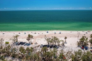 A beach with a parking lot and a view of the ocean.