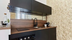Een moderne keuken met donkere kasten, een RVS-spoelbak en een inbouwoven.