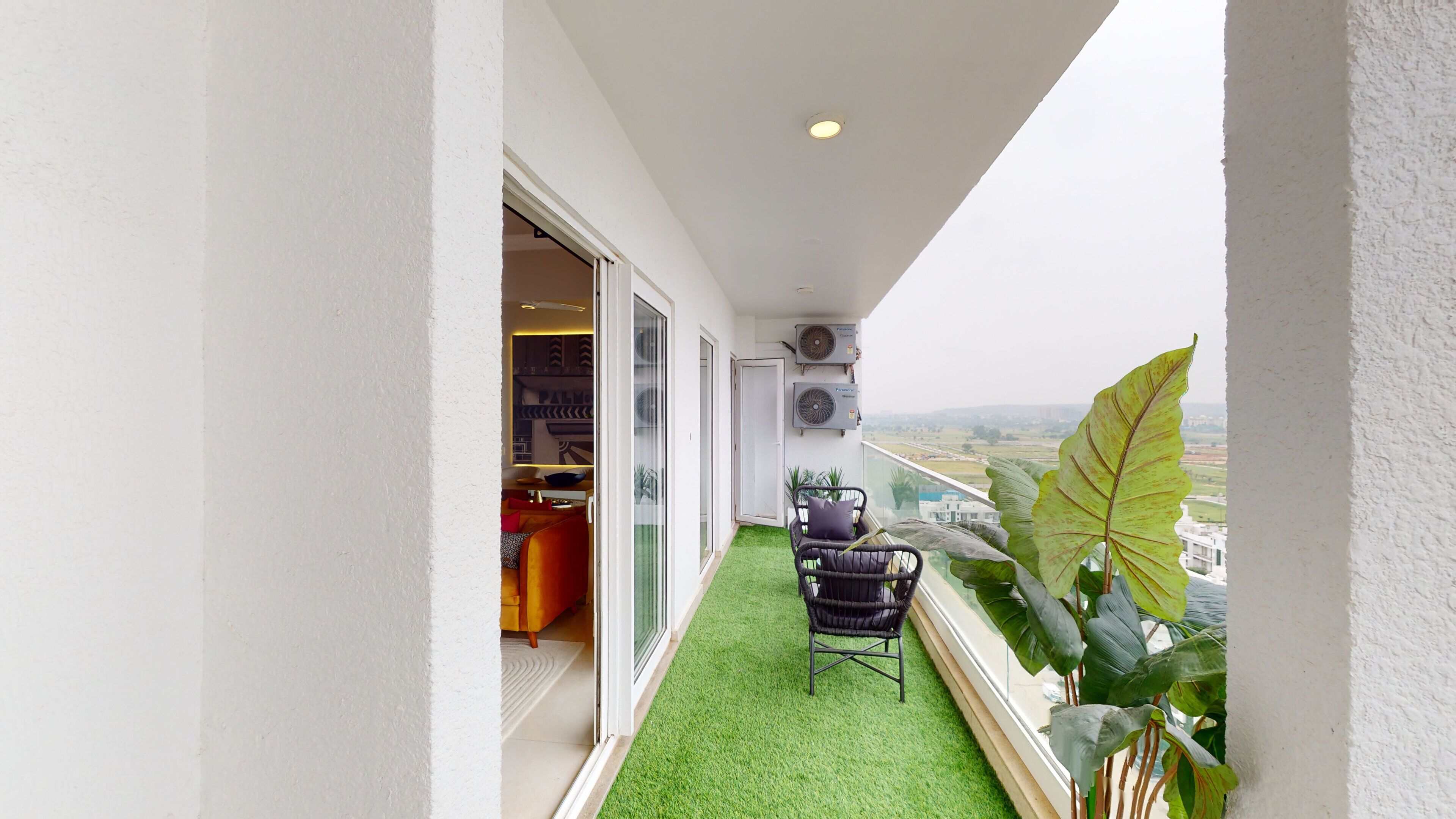 A balcony with artificial grass, a chair, and a large plant.