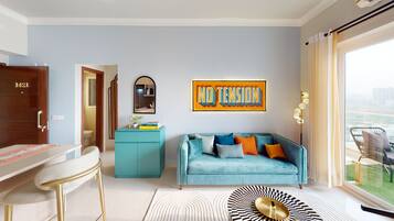 Un salon moderne avec un canapé de couleur turquoise, une table basse agrémentée d’un plateau décoratif, un meuble bleu et une grande fenêtre donnant sur des immeubles.