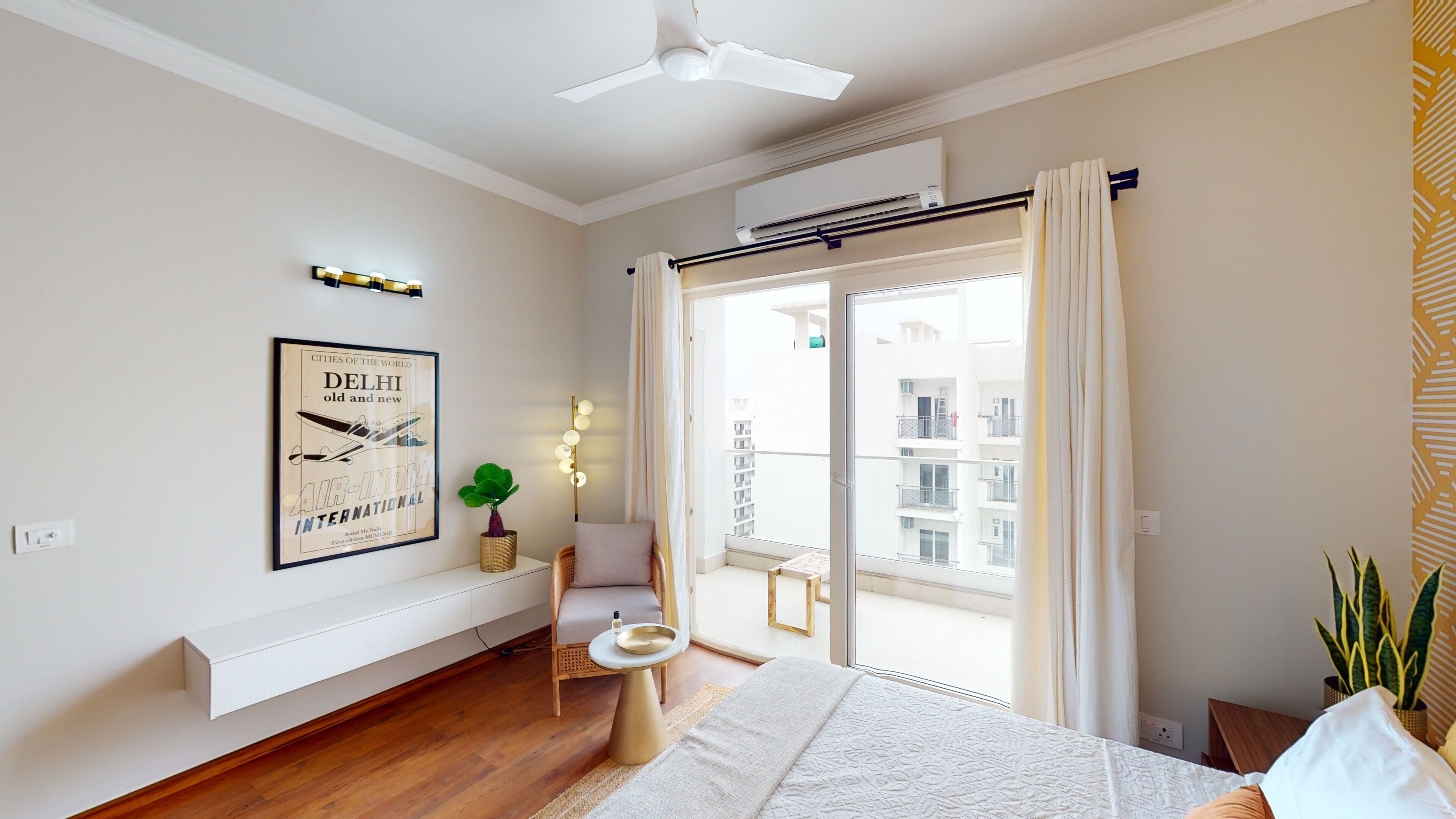 Una habitación de hotel moderna con una cama grande, un rincón de descanso, un balcón con vistas a la ciudad y un ventilador de techo.