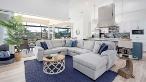 Una sala moderna con un sofá modular, una mesa de centro y vistas a la cocina.