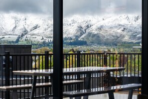A balcony with wooden furniture overlooking a snowy mountain landscape. - Peaks and Pines Wanaka (Wānaka)