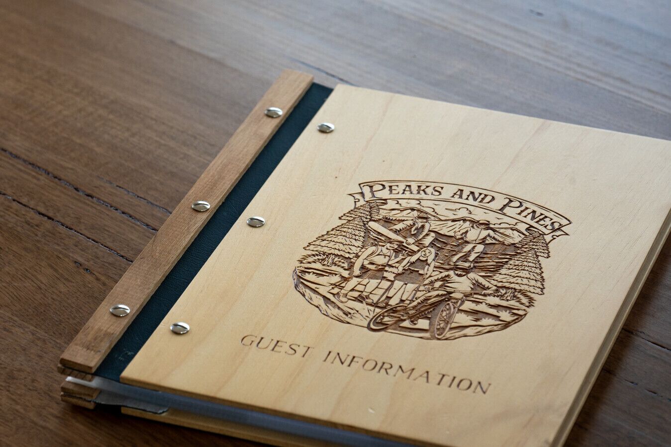 Un libro informativo para huéspedes con el título "PEAKS AND PINE'S" e ilustración detallada de un paisaje montañoso.