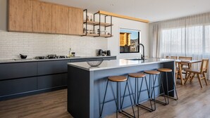 Una cocina moderna con una isla central, taburetes de bar y un comedor con vistas.